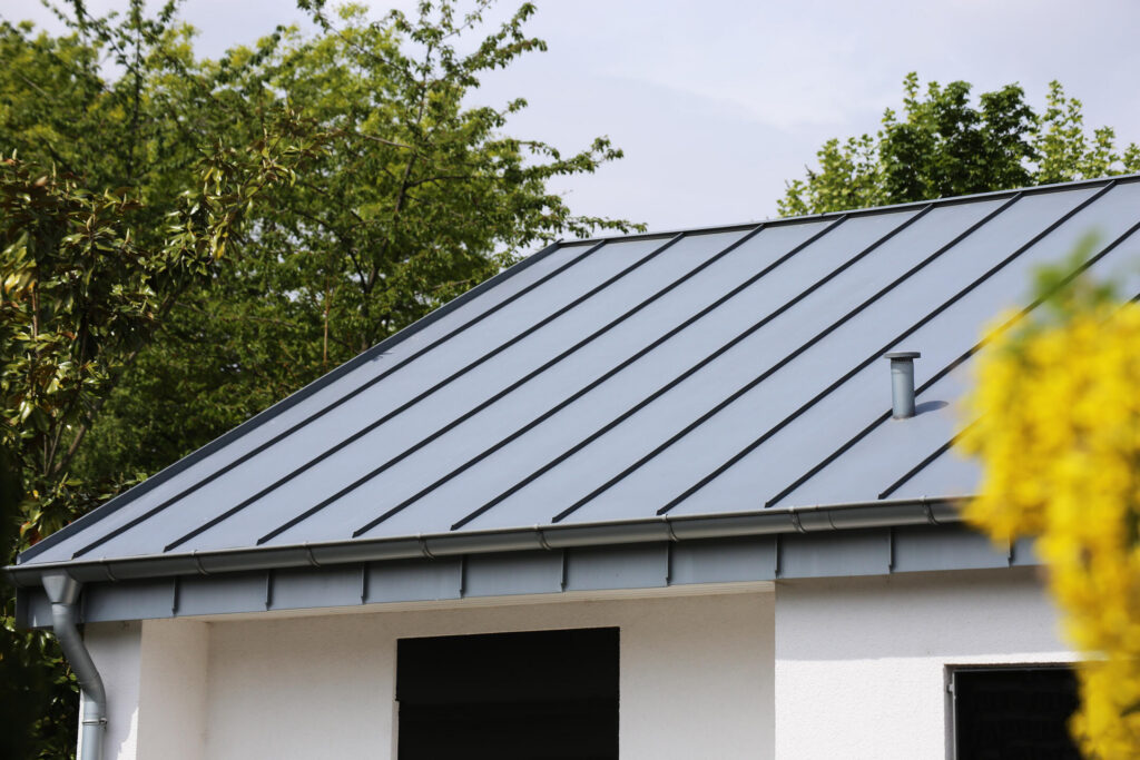 how long does a metal roof last-gray standing seam metal roofing on white sided house